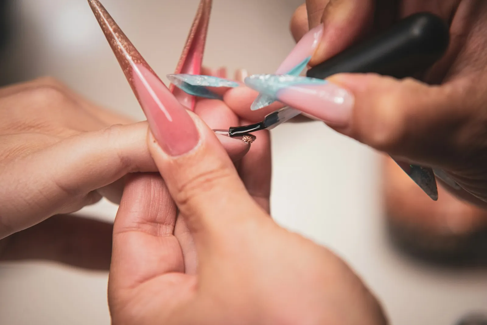 Nail technician shaping and painting long nail extensions