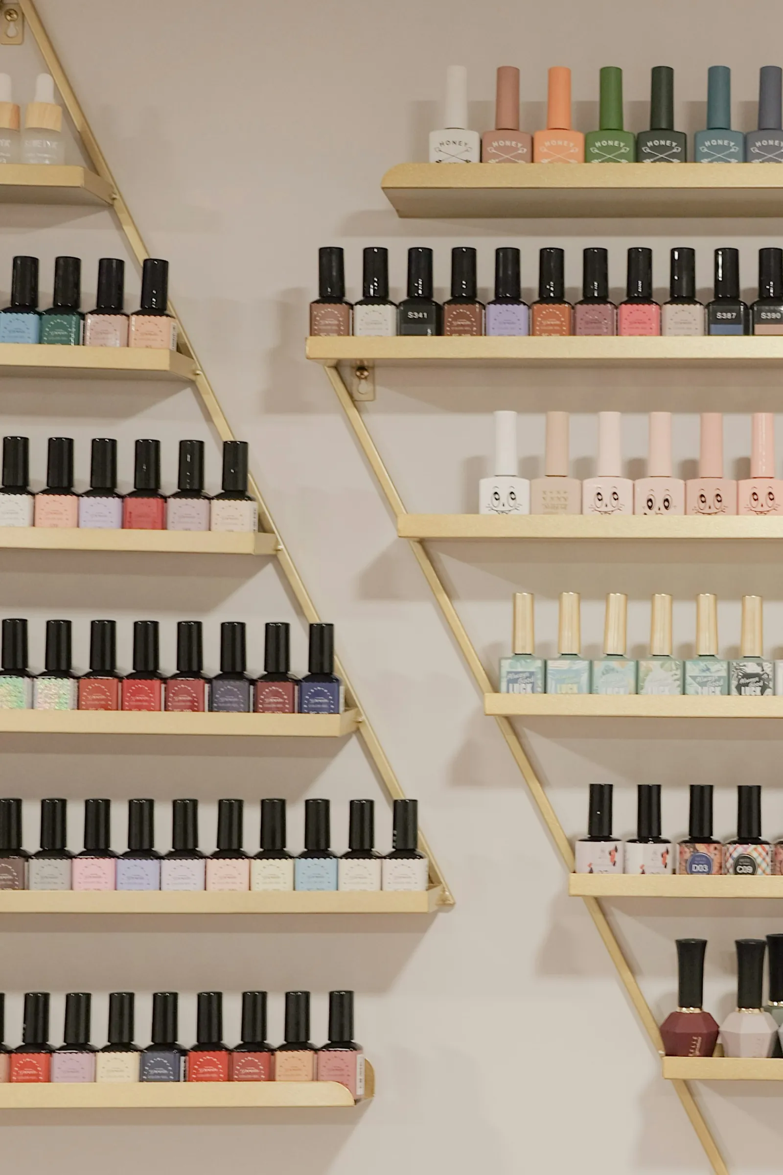 Wall of colorful nail polish bottles on gold shelves